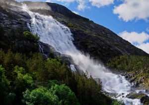 Langfoss waterfall flowing down a steep green mountain into Åkrafjorden in Norway