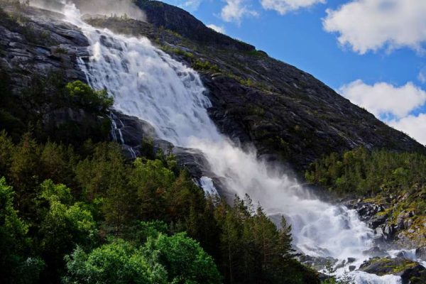 Langfoss waterfall flowing down a steep green mountain into Åkrafjorden in Norway