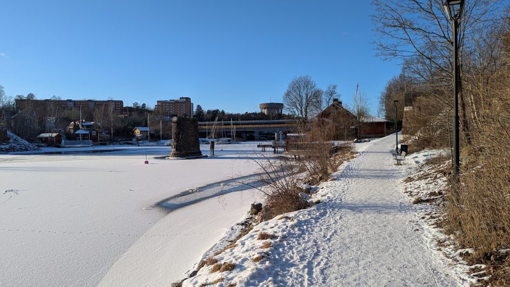 Wide view of the old Stocksundsbro bridge support, the new Stocksundsbro bridge, and a clear blue winter sky